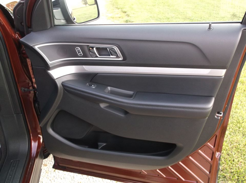 Interior of a 2016 Ford Explorer driver's door, showing black leather armrest and silver trim