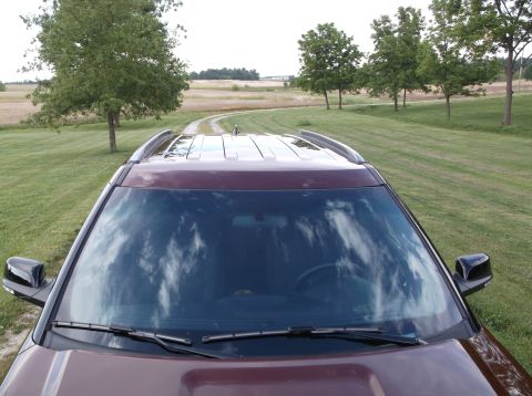 2016 Ford Explorer - The front of a maroon SUV is shown from a high angle, with a rural landscape in the background.
