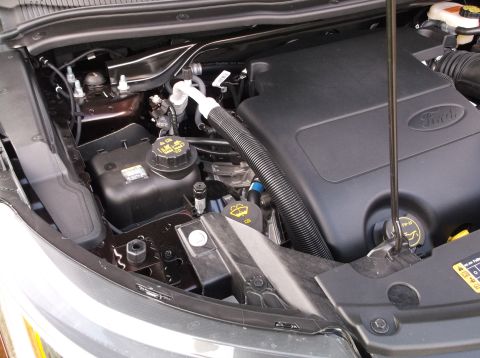 2016 Ford Explorer - Close-up view of a Ford engine bay, showing various components and the Ford logo on the engine cover.