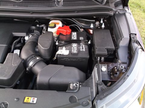 2016 Ford Explorer - The engine bay of a vehicle, showing the battery, air intake system, and fuse box.