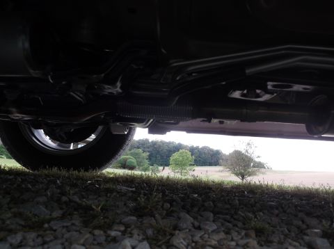2016 Ford Explorer - The underside of a vehicle is visible, with a view of the suspension and exhaust components against a backdrop of trees and a field.
