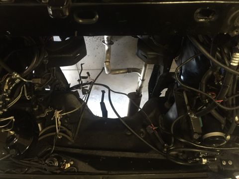 1982 Ford Bronco - The underside of a vehicle reveals its engine bay and exhaust system, with various hoses and wiring visible.