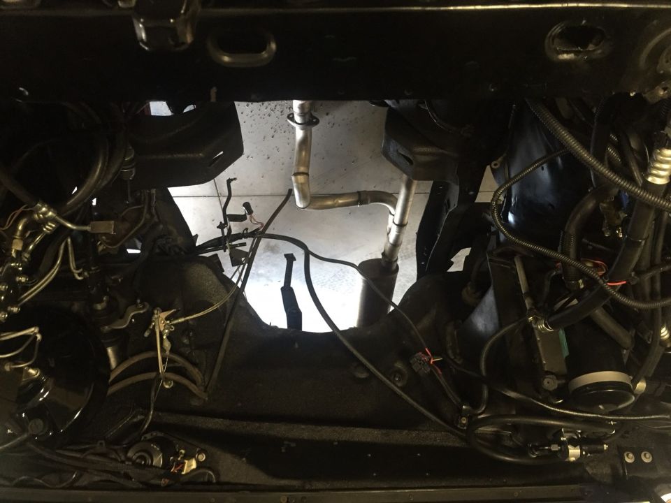 Undercarriage of a vehicle with exposed engine components and exhaust pipes