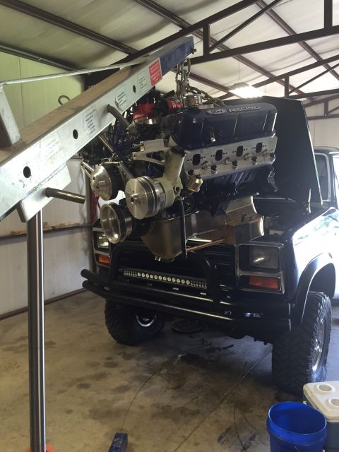 1982 Ford Bronco - The engine is being removed from the vehicle using an engine hoist.