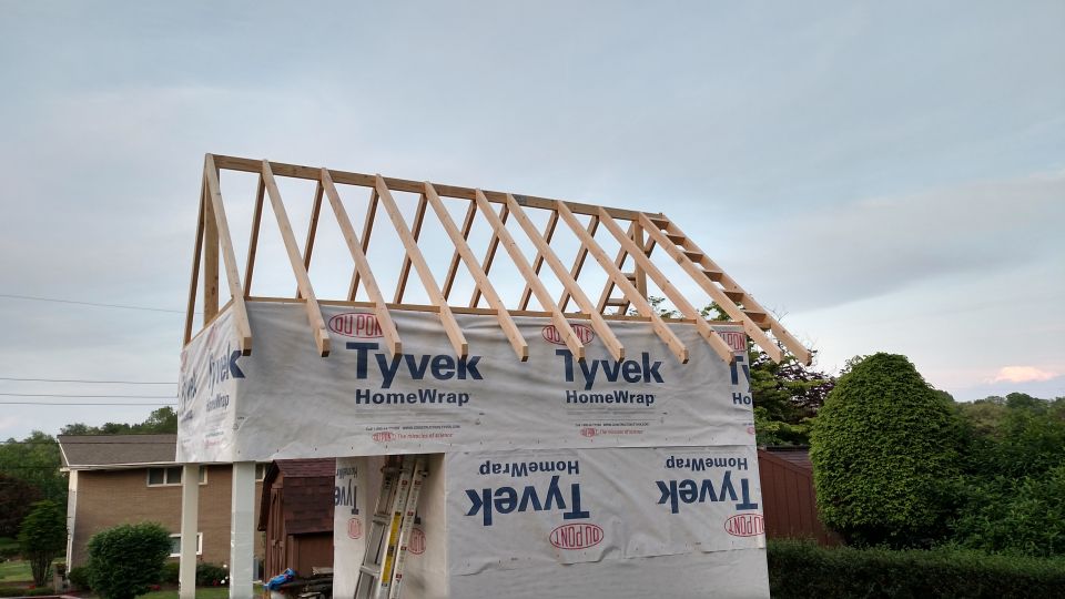 Building under construction with wooden roof trusses and Tyvek house wrap visible