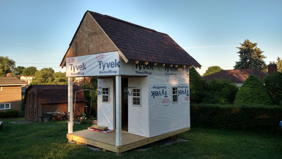 playhouse being built, covered in Tyvek wrap, with a small porch and windows