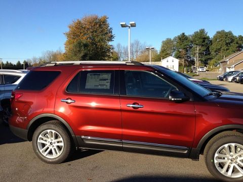2016 Ford Explorer - A red SUV is parked in a lot with other vehicles under a clear blue sky.