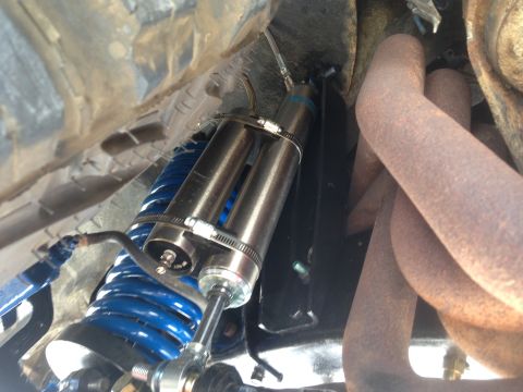 1979 Ford Bronco - The image shows a close-up view of a vehicle's suspension system, including a shock absorber and coil spring, alongside exhaust pipes.