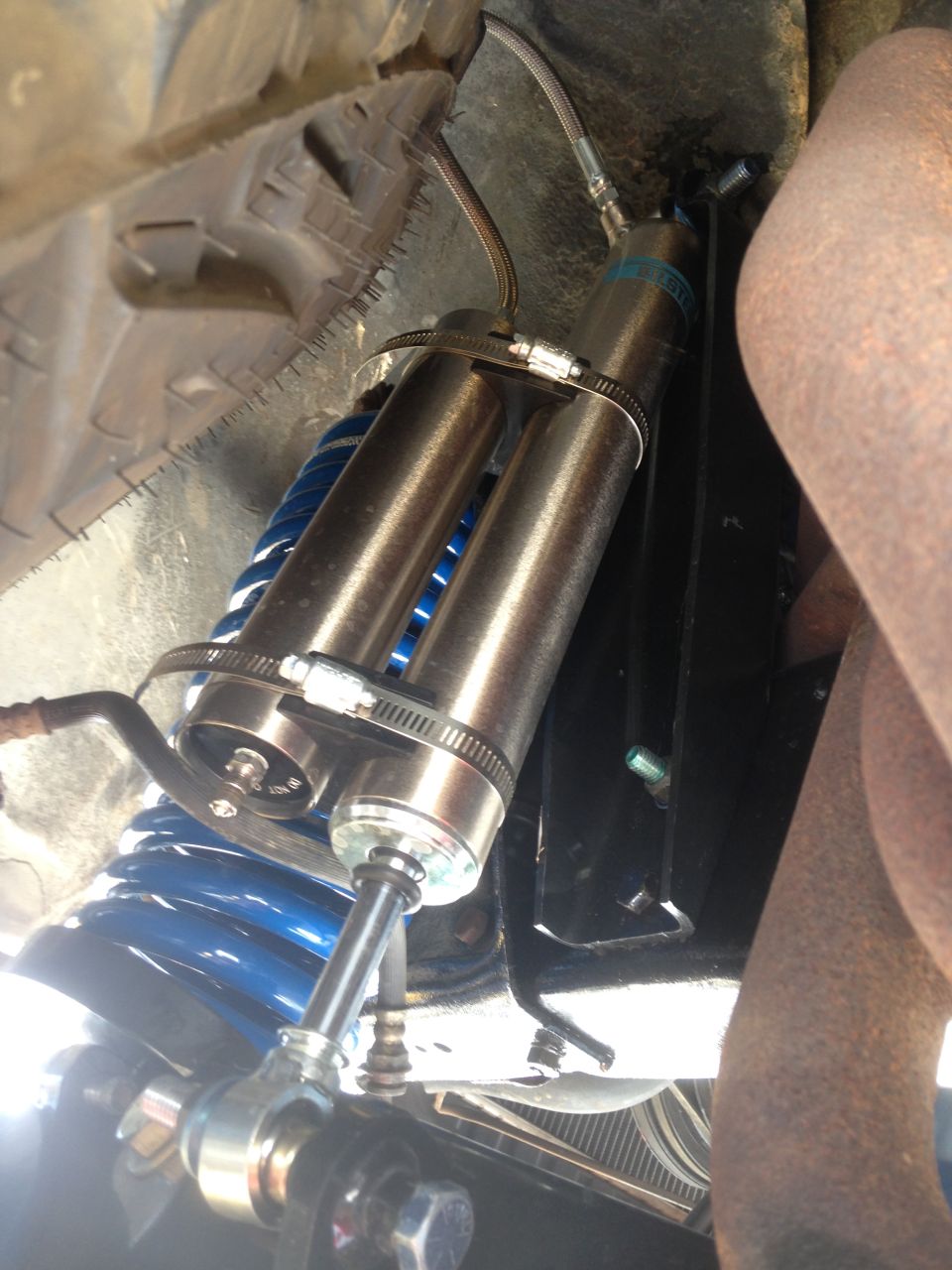 Dual shock absorbers with blue coil springs mounted to a vehicle's undercarriage