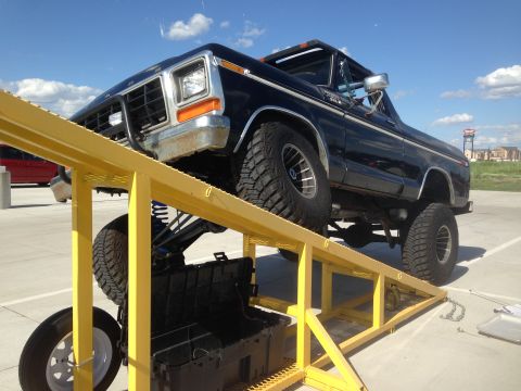 1979 Ford Bronco - A black 1979 Ford Bronco is shown with its suspension elevated on a yellow ramp.