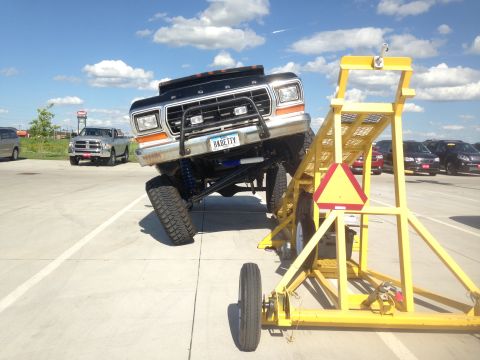 1979 Ford Bronco - A heavily modified Ford truck is positioned on a trailer, with other vehicles visible in the background.