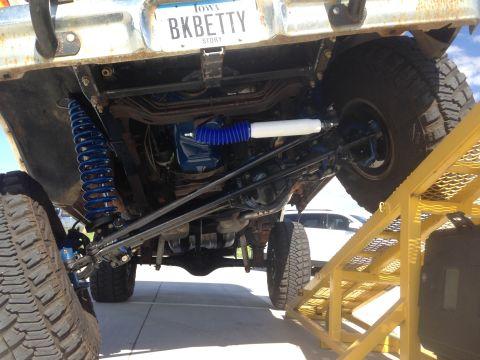 1979 Ford Bronco - The underside of a 1979 Ford Bronco shows off its upgraded suspension system with prominent blue coilover shocks.
