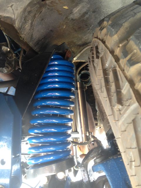 1979 Ford Bronco - Close-up view of a bright blue coil spring and shock absorber, part of a vehicle's suspension system.