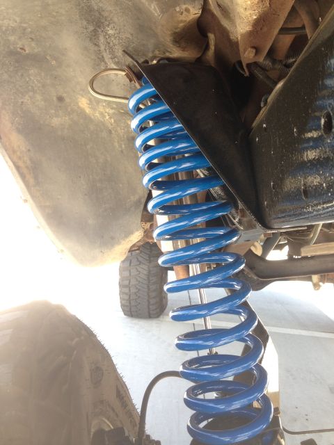 1979 Ford Bronco - The underside of a vehicle shows a bright blue coil spring and part of the tire.