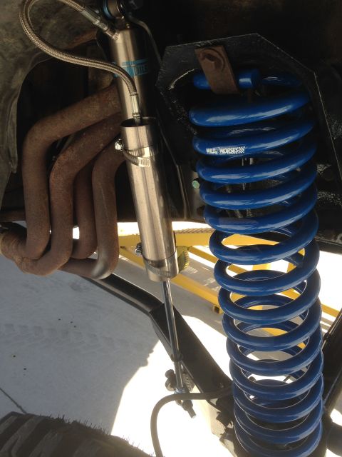 1979 Ford Bronco - Close-up of vehicle suspension components including a blue coil spring and silver shock absorber.