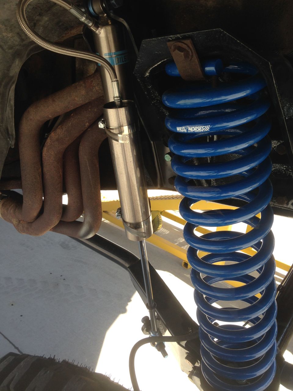 Blue coil spring and silver shock absorber with rusty exhaust manifold