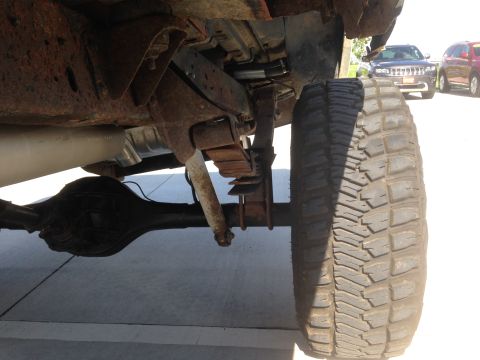 1979 Ford Bronco - The rear suspension and axle of a vehicle are shown, with other vehicles in the background.
