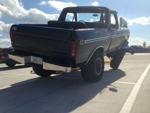1979 Ford Bronco - Rear view of a lifted black Ford Bronco on a jack, with a custom bumper and license plate.