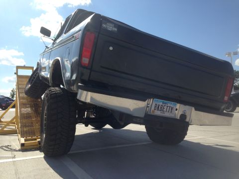 1979 Ford Bronco - A black Ford Bronco is shown on a ramp, highlighting its lifted suspension and large tires.