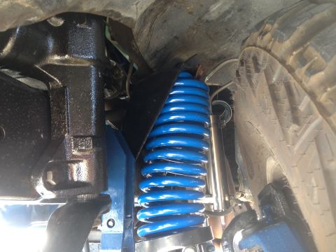 1979 Ford Bronco - Underside view of a vehicle's suspension system, focusing on a bright blue coil spring.