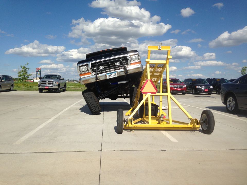 Black Ford F-Series truck with lifted suspension on a yellow ramp