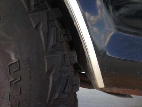 1979 Ford Bronco - A close-up view shows a vehicle's tire and fender, with some rust visible on the lower body panel.