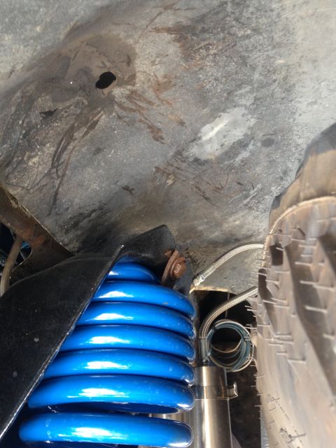 1979 Ford Bronco - Close-up view of blue coil springs and suspension components within a vehicle's wheel well.