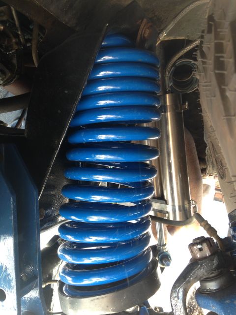 1979 Ford Bronco - Close-up of a blue coil spring and shock absorber, likely from a vehicle's suspension system.