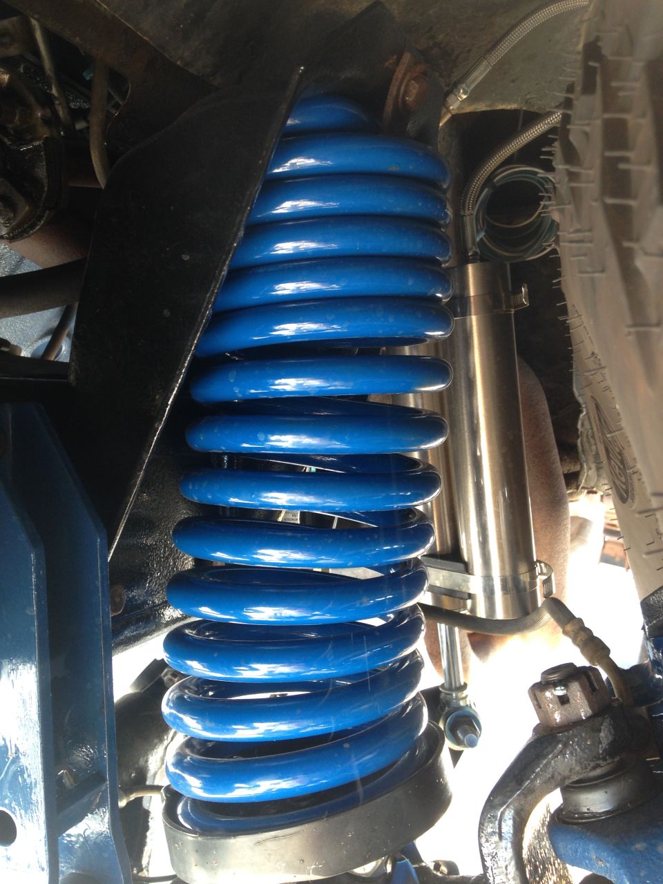 Blue coil spring and silver shock absorber assembly, part of vehicle suspension