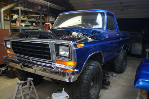 1979 Ford Bronco - A blue Ford Bronco is undergoing maintenance in a cluttered garage.