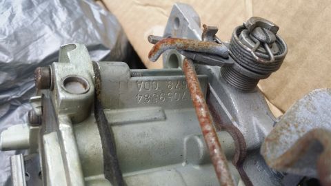 1978 Chevrolet C/K Pickup - Close-up of a carburetor part with visible stamped numbers and rusty linkage.