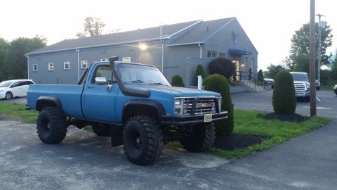 1978 Chevrolet C/K Pickup - Blue 1978 Chevrolet C/K Pickup with snorkel and lifted suspension parked outside a building.