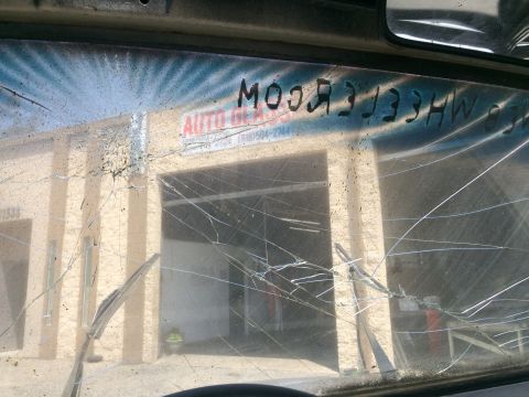1987 Suzuki Samurai - Windshield is heavily cracked, obscuring the view of an auto glass shop.
