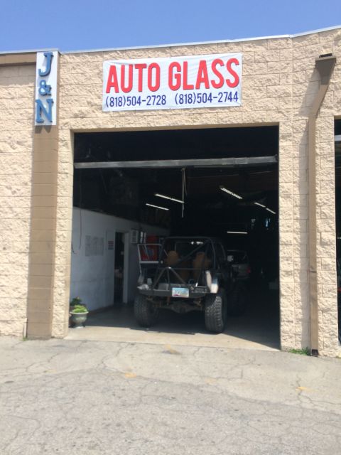 1987 Suzuki Samurai - A modified off-road vehicle is parked inside a garage with an 'Auto Glass' sign above the entrance.