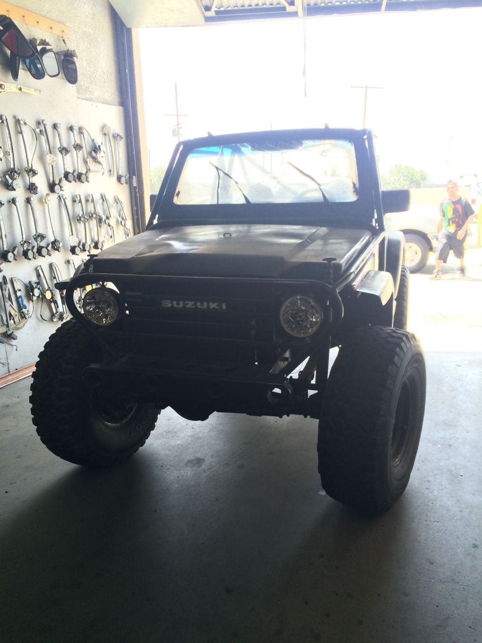 Black 1987 Suzuki Samurai with large tires and aftermarket lights