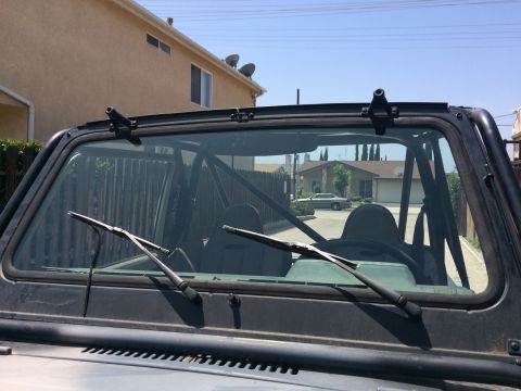 1987 Suzuki Samurai - View through the windshield of a 1987 Suzuki Samurai, showing the interior roll cage and seats.