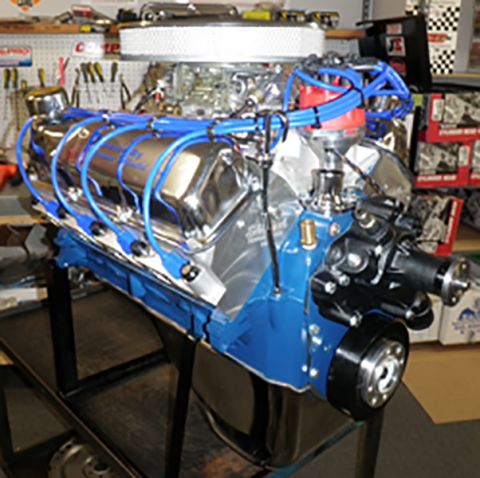 1978 Ford Bronco - A V8 engine with chrome accents and blue wiring is displayed on a stand in a workshop.