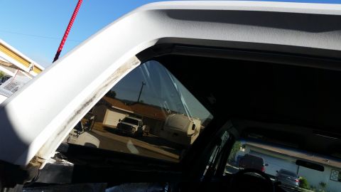 1992 Ford Bronco - Reflection of a white pickup truck and RV in the window of a vehicle.