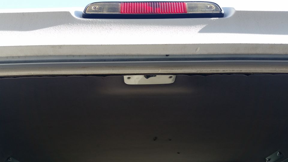 Interior view of a vehicle's rear cargo area, showing the upper trim and third brake light