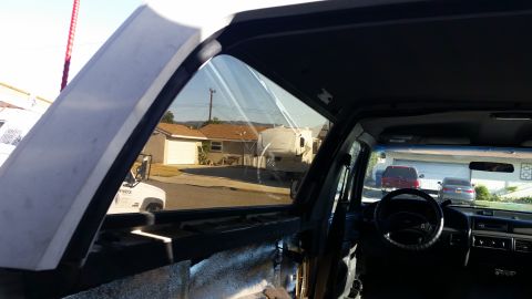 1992 Ford Bronco - The interior of a 1992 Ford Bronco is visible through the open driver's side window, with a suburban street in the background.