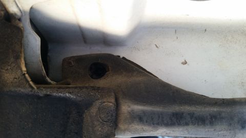 1992 Ford Bronco - This is a close-up view of a vehicle's frame bracket, showing a mounting hole and some surface wear.