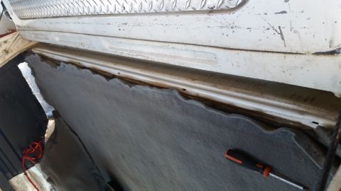 1992 Ford Bronco - Close-up view of interior trim and carpet being removed from a vehicle, revealing the underlying metal structure.