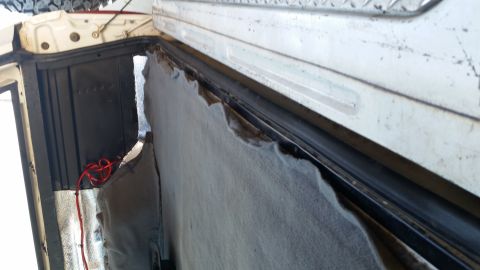 1992 Ford Bronco - Torn upholstery and exposed wiring inside a vehicle's rear compartment.