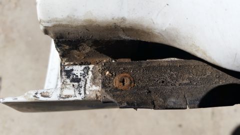 1992 Ford Bronco - Close-up of a dirty and rusted automotive trim piece, likely from the rear of a vehicle.