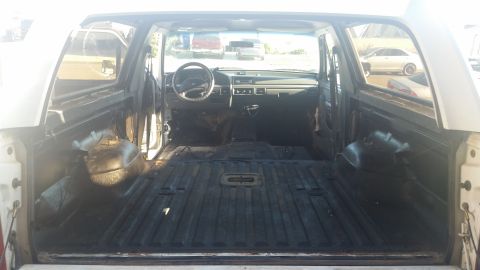 1992 Ford Bronco - The interior of the vehicle is stripped down, revealing the bare floor and dashboard.