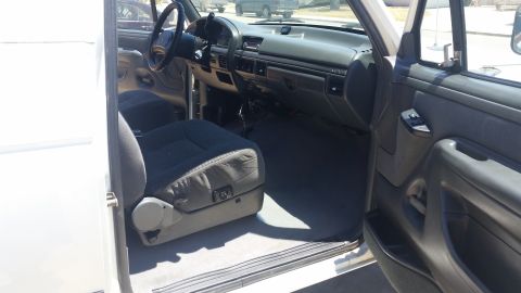 1992 Ford Bronco - The interior of a white Ford truck is shown, the driver's seat and dashboard.