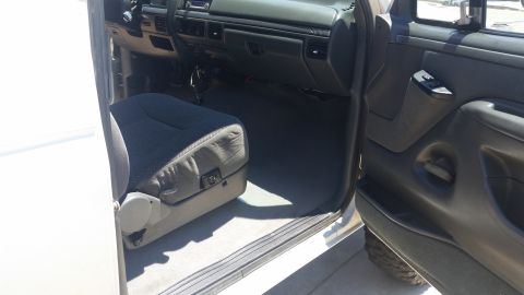 1992 Ford Bronco - The interior of a white vehicle is visible, including the driver's seat and dashboard.
