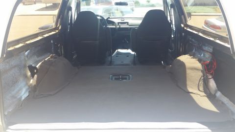1992 Ford Bronco - The interior of a vehicle is shown, the empty cargo space and the front seats.