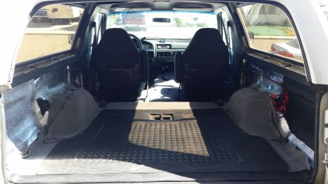 1992 Ford Bronco - The interior of a vehicle shows the front seats, dashboard, and the empty cargo space behind them.