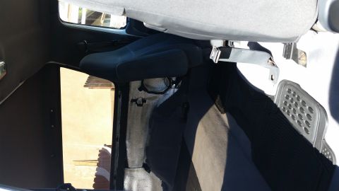 1992 Ford Bronco - The interior of the vehicle shows dark blue seats and gray carpeting, with a view through the window to the outside.
